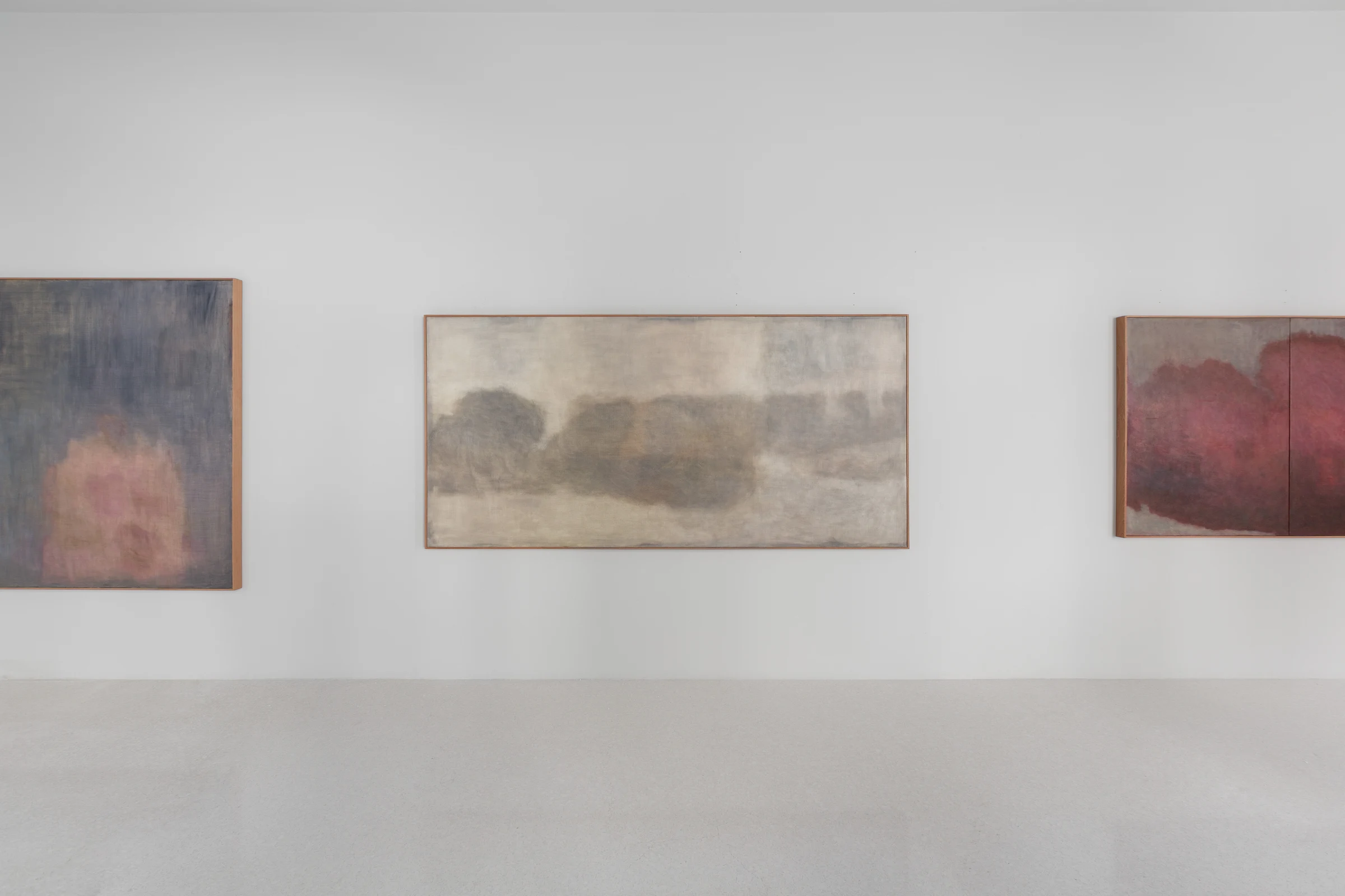 Three abstract paintings by Nuria Maria installed across a white gallery wall.